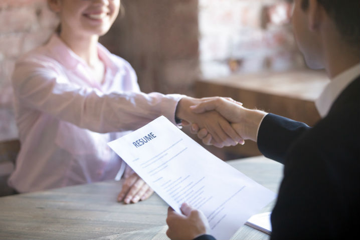 Woman shaking hand of interviewer who is holding resume